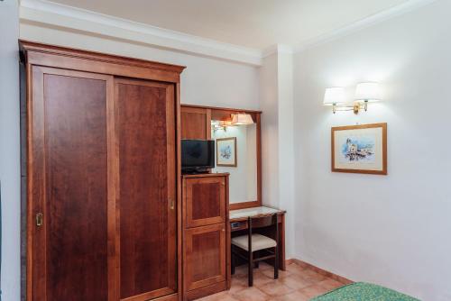a room with a wooden cabinet and a desk with a television at Hotel Montana in Massa Lubrense