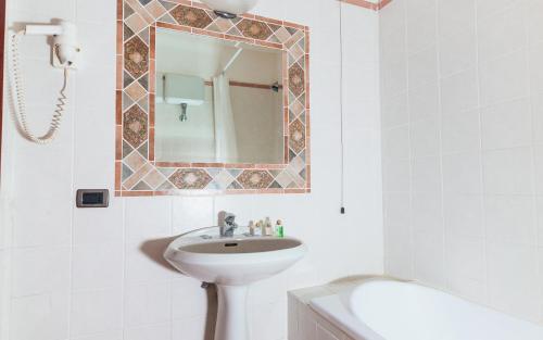 a white bathroom with a sink and a mirror at Hotel Montana in SantʼAgata sui Due Golfi