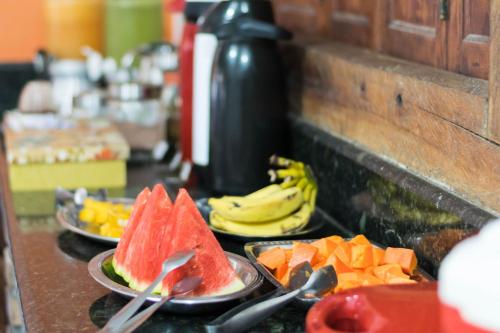 tres platos de fruta en un mostrador con cucharas y cucharas en Pousada Holú, en Itaúnas