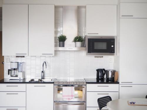 a white kitchen with a stove and a microwave at 2ndhomes Tampere "Rooftop" Apartment - Ratina 7th Floor Apt with Amazing Lake View in Tampere