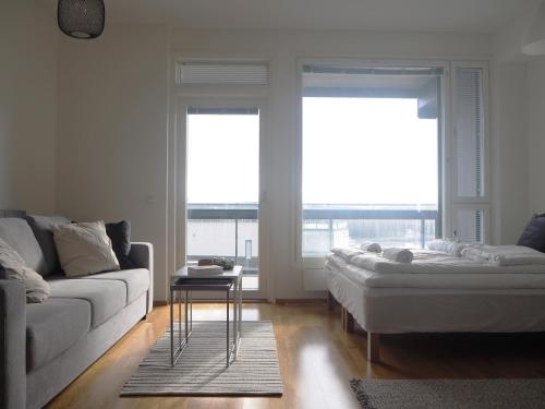 a living room with a couch and two large windows at 2ndhomes Tampere "Rooftop" Apartment - Ratina 7th Floor Apt with Amazing Lake View in Tampere