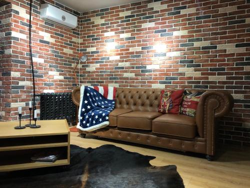 a living room with a brown couch and a brick wall at Kurmangazi 154-7 in Oral