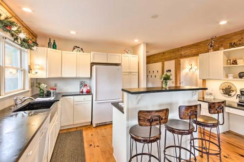 a kitchen with white cabinets and bar stools at Quaint Creston Hideaway with Mtn Views and Hot Tub! in Creston