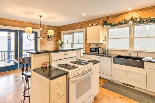 a kitchen with white appliances and wooden walls at Quaint Creston Hideaway with Mtn Views and Hot Tub! in Creston