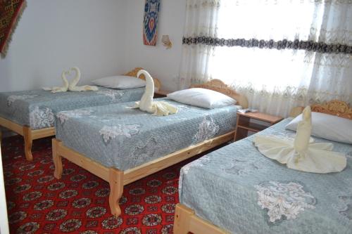 2 Betten in einem Zimmer mit Schwänen darauf in der Unterkunft Khiva Karim Sulton in Xiva
