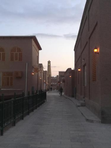an empty street with a clock tower in the distance at Khiva Karim Sulton in Khiva
