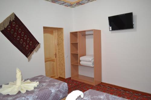 a room with a bed and a tv on a wall at Khiva Karim Sulton in Khiva