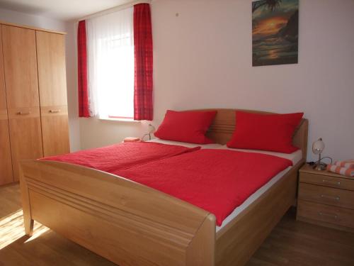 a bedroom with a large wooden bed with red pillows at Ferienhaus Hubertus in Elend mit Balkons in Elend
