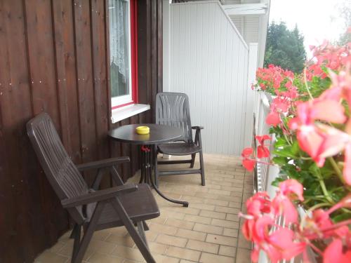 two chairs and a table on a patio with flowers at Ferienhaus Hubertus in Elend mit Balkons in Elend