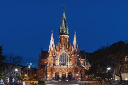 a large cathedral building with a clock tower at night at Modern Studio Węgierska Cracow by Renters in Krakow