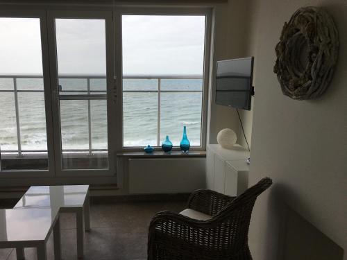 
a room with a chair and a window overlooking the ocean at appartement seafront in Ostend

