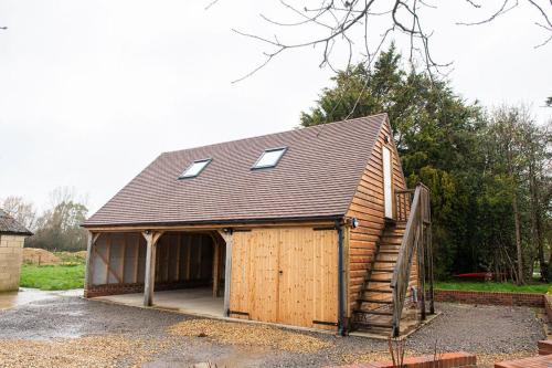 uma grande garagem de madeira com um telhado com janelas em The Barn em Chichester