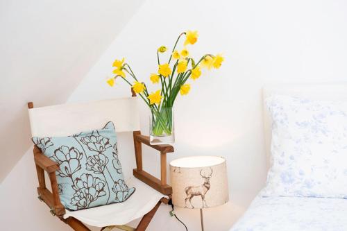 a vase with yellow flowers and a lamp next to a bed at The Barn in Chichester