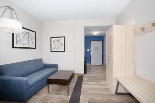 a living room with a blue couch and a hallway at Holiday Inn Express & Suites Phoenix Glendale Dist by IHG in Glendale