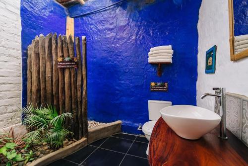 a blue bathroom with a white toilet and a blue wall at Kimbas Bungalows Mancora in Máncora