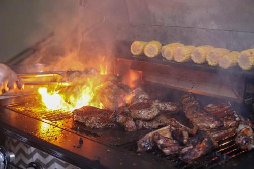 a person cooking meat on a grill with flames at Hotel RH Boutique Aruba in Oranjestad