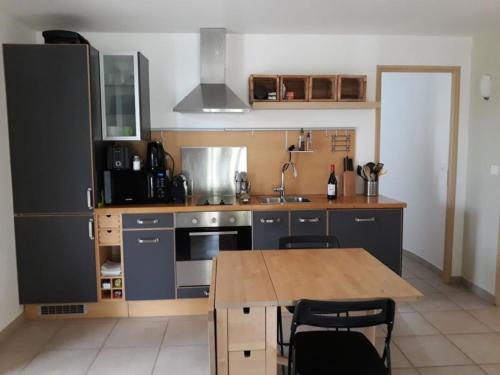 eine Küche mit einem Holztisch und einer Arbeitsplatte in der Unterkunft Parfums de Provence "Le Lavandin" Piscine chauffée & Spa in Vaison-la-Romaine