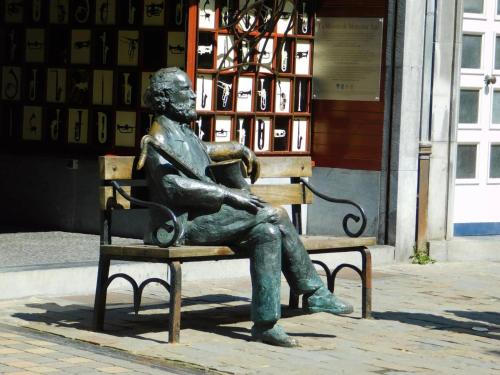 a statue of a man sitting on a bench at Les rives de Sax in Dinant