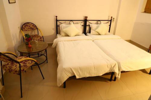 two beds in a room with a table and chairs at TOURIST VILLAGE KHAJURAHO in Khajurāho