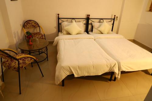 a bedroom with two beds and a table and a chair at TOURIST VILLAGE KHAJURAHO in Khajurāho
