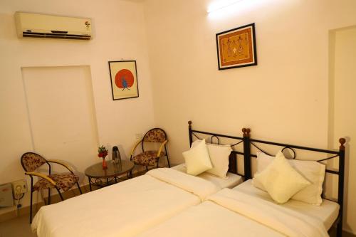 a bedroom with two beds and a table and chairs at TOURIST VILLAGE KHAJURAHO in Khajurāho