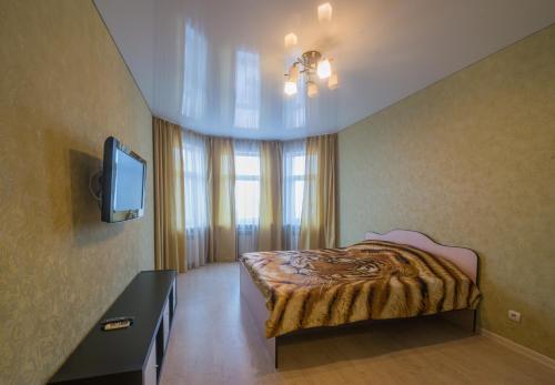 1 dormitorio con 1 cama, TV y ventana en Apartments u Kremlya, en Kazán