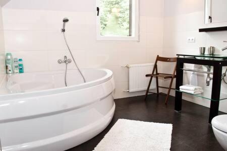 ein weißes Badezimmer mit einer Badewanne und einem Waschbecken in der Unterkunft DOM 4 POKOJE Z BASENEM BLISKO WARSZAWY in Józefów