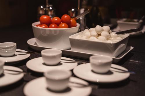 a table with plates and cups and a bowl of tomatoes at FIORI Dolomites Experience Hotel in San Vito di Cadore