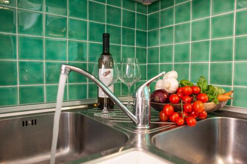 a sink with a bowl of vegetables and wine glasses at DomoMea - Villetta Poseidone in Costa Rei