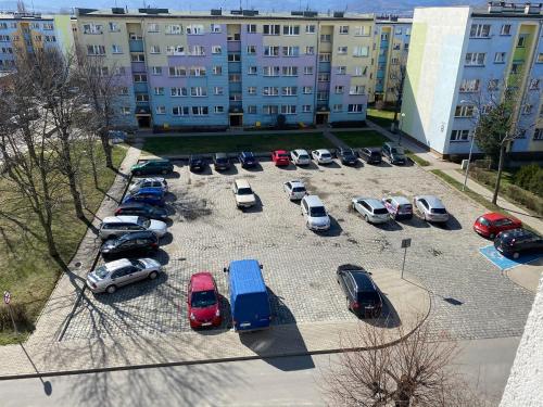a parking lot with cars parked in front of a building at APARTAMENT OŚ. BŁĘKITNE 10H in Dzierżoniów