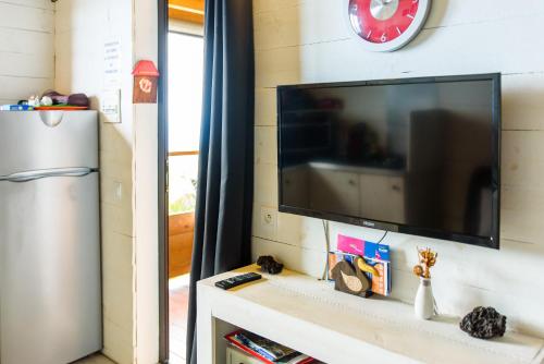 a flat screen tv sitting on a shelf next to a refrigerator at Ré Océan in Saint-Leu