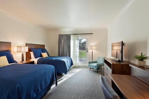 a hotel room with two beds and a television at La Playa Inn Santa Barbara in Santa Barbara
