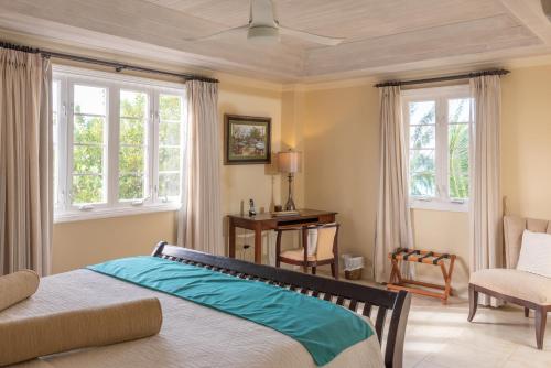 a bedroom with a bed and a desk and windows at White Sands Beach Condos in Christ Church