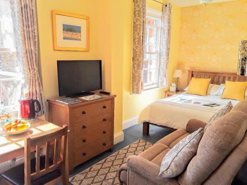 ハイスにあるThe Old Post Office Boutique Guesthouseのベッド、テレビ、ソファのある寝室