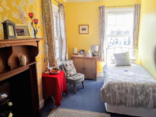 a bedroom with a bed and a chair and a window at The Old Post Office Boutique Guesthouse in Hythe