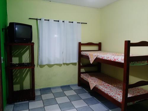a room with a tv and two bunk beds at Pisco Chalés in Ubatuba