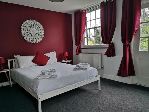 a bedroom with a bed with red walls and windows at The Red Lion in Hythe