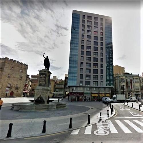 a statue in the middle of a city with a building at ALBOR II in Gijón