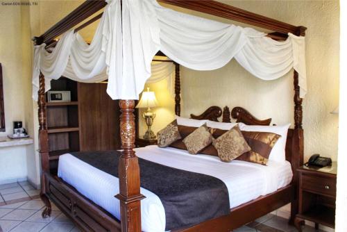 a bedroom with a canopy bed with pillows at Hotel Posada Virreyes in Guadalajara