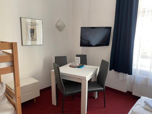 a room with a white table and chairs and a tv at Bornholmer Hof im Prenzlauer Berg in Berlin