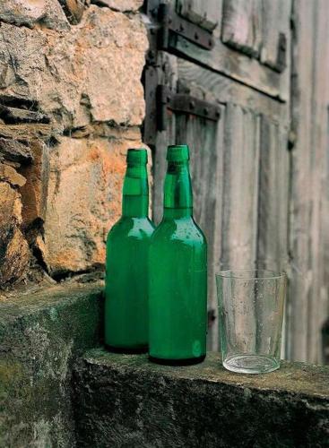 two green bottles sitting on a ledge next to a glass at ALBOR II in Gijón