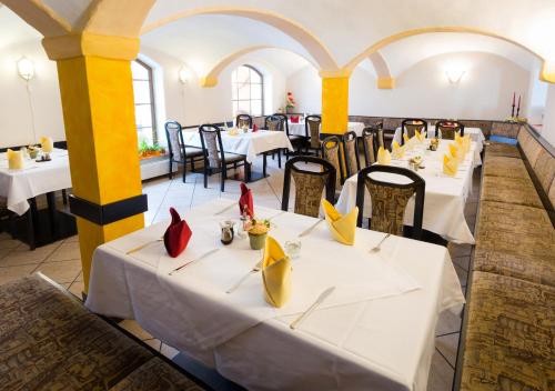 a restaurant with white tables and chairs with yellow napkins at Hotel & Ferienwohnungen Bohlenblick in Saalfeld