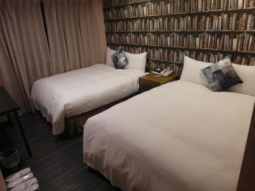 a hotel room with two beds and a book wall at Hotel Fun - Linsen in Taipei