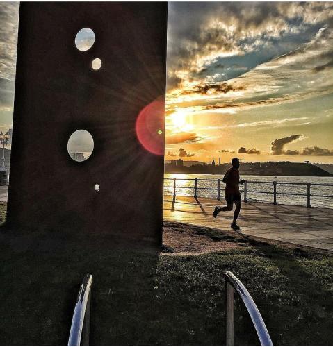 a man running on a sidewalk near the water at ALBOR II in Gijón