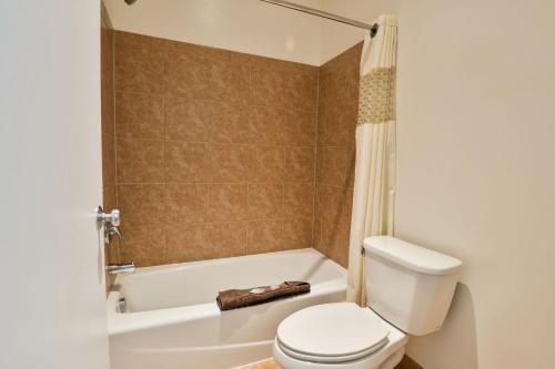 a bathroom with a white toilet and a bath tub at Adventure Inn Moab in Moab