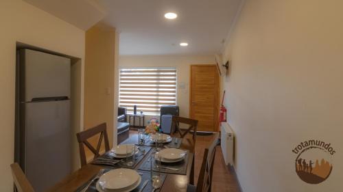 a dining room with a table and chairs and a kitchen at Trotamundos in Puerto Natales