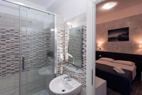 a bathroom with a shower and a sink and a bed at TIBURTINA INN GUEST HOUSE in Rome