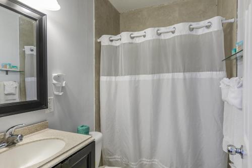 a bathroom with a white shower curtain and a sink at Hollywood Broadwalk Oceanside Hotel in Hollywood