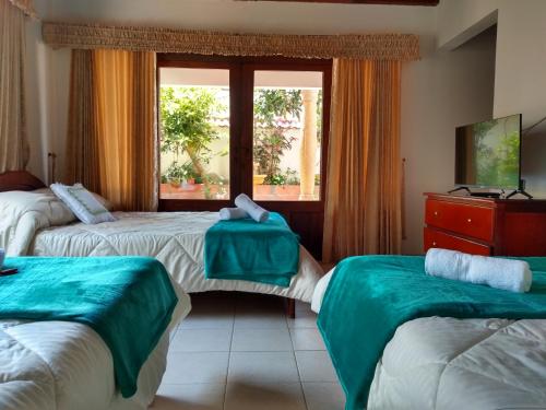 a hotel room with two beds and a window at Hospedaje Casa Marsella in Villa de Leyva