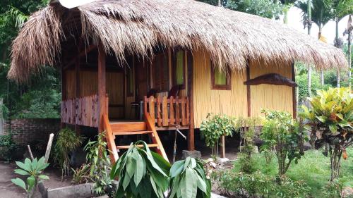 une petite cabane avec un toit de chaume et une terrasse couverte dans l'établissement Lena house Flores, à Hitokalak